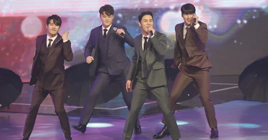 Korean trot singer performing on stage in a glittering suit with dramatic lighting.