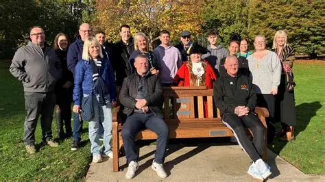 Solar-lit wooden mental health bench in a UK park with supportive message carved into it