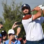Jon Rahm walks onto the golf course during a European Tour event, holding his club and looking focused amid uncertainty over Ryder Cup eligibility
