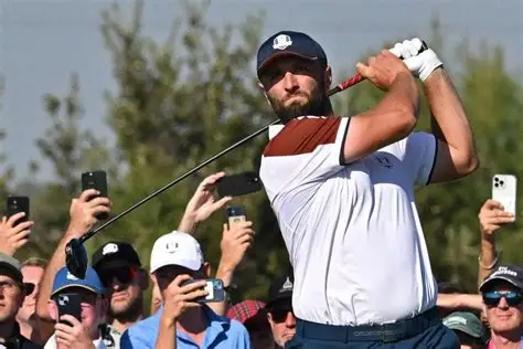 Jon Rahm walks onto the golf course during a European Tour event, holding his club and looking focused amid uncertainty over Ryder Cup eligibility