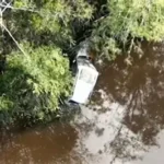 Submerged car found in Queensland floodwaters during search for missing backpackers.