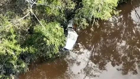 Submerged car found in Queensland floodwaters during search for missing backpackers.