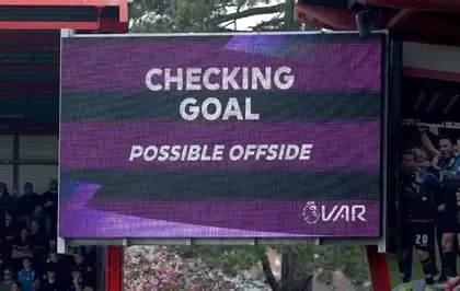 VAR decision being reviewed during a Premier League match with players waiting