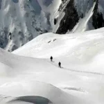 Rescue helicopter flying over avalanche-affected slopes in the French Alps.