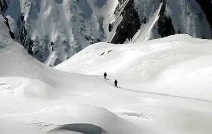 Rescue helicopter flying over avalanche-affected slopes in the French Alps.