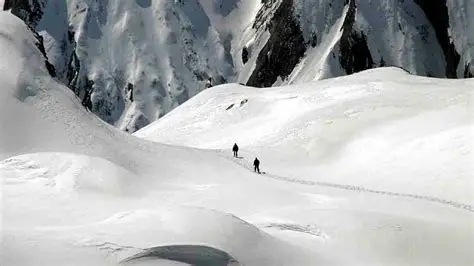 Rescue helicopter flying over avalanche-affected slopes in the French Alps.