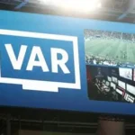 Football referee reviewing VAR decision during a match in European league
