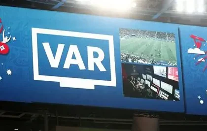 Football referee reviewing VAR decision during a match in European league
