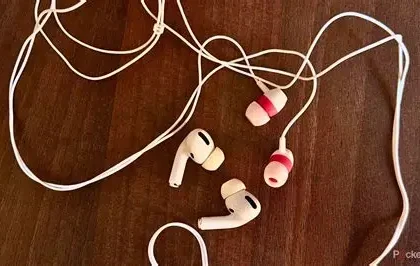 Person listening to music using wired headphones connected to a smartphone.