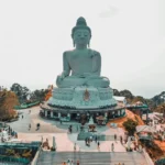 Dark side of luxury travel tourism at large Buddha statue Phuket Thailand