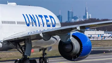 United Airlines passenger dons headphones on flight while neighbor glares at phone audio blasting without courtesy.