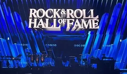 Oasis band members performing live on stage with a large crowd in the background.