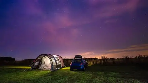 Person sleeps peacefully in tent under starry sky with campfire glow, surrounded by forest embodying natural circadian rhythm reset.