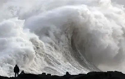 Wind-swept UK coastal town battered by storm waves under dark skies, illustrating named weather events like Chandra.
