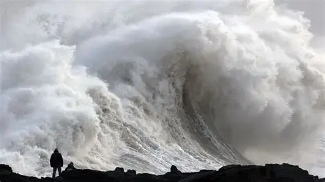Wind-swept UK coastal town battered by storm waves under dark skies, illustrating named weather events like Chandra.