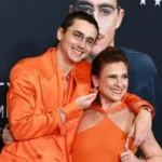 Timothée Chalamet speaking at a public event with a theatre stage in the background.