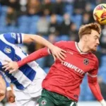 John Terry watches from Colchester United stands during League Two match against Accrington, amid takeover rumors.