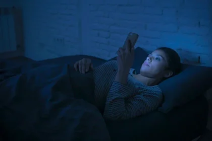 Person using smartphone at night with dim lighting affecting sleep patterns