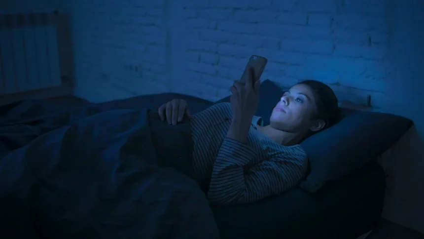 Person using smartphone at night with dim lighting affecting sleep patterns