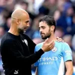 Manchester City captain Bernardo Silva celebrates EFL Cup win as Pep Guardiola watches intently from touchline.