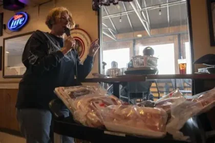 Excited winner grabs wrapped meat prizes including steaks and pork chops at Minnesota meat raffle event.