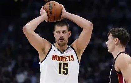Nikola Jokic drives past Victor Wembanyama in intense Nuggets-Spurs overtime battle, crowd roaring in background.