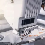 Garment manufacturing robot applying adhesive to fabric seams to automate clothing production in 2026