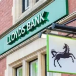 Woman holding HMRC cheque outside rural post office during Lloyds cheque deposit dispute