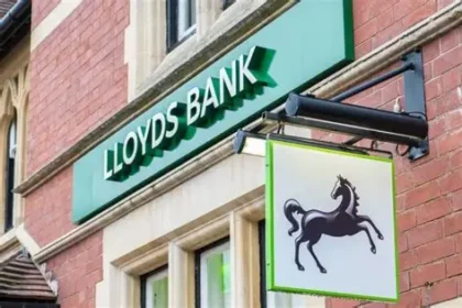 Woman holding HMRC cheque outside rural post office during Lloyds cheque deposit dispute